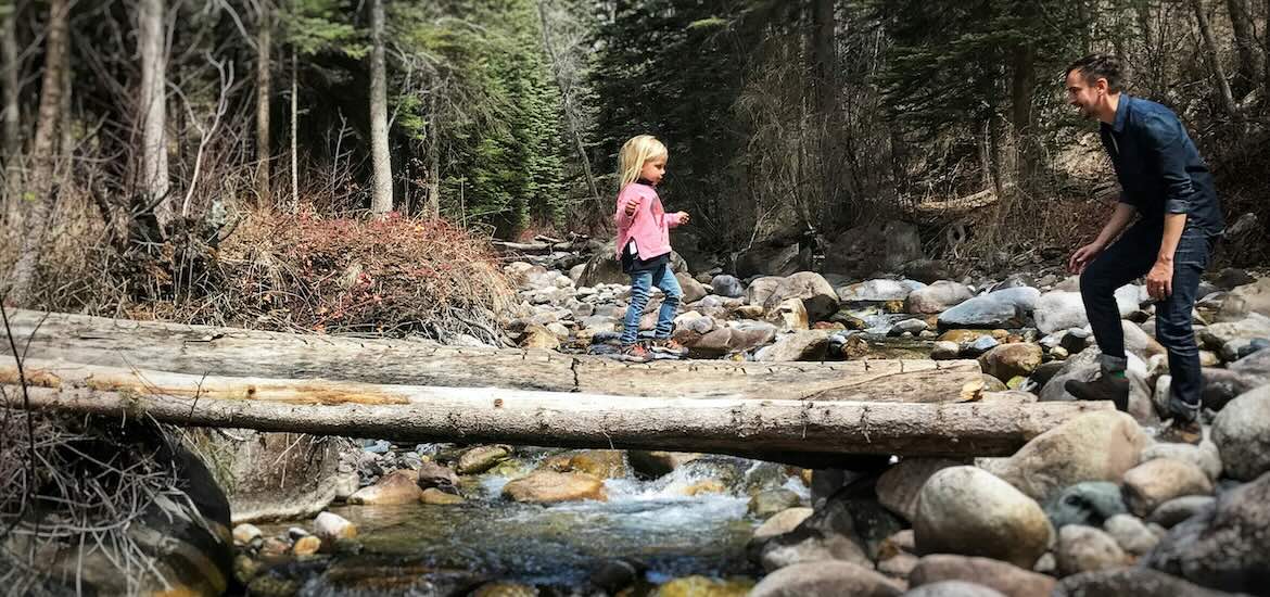 Dad and daughter on log over river