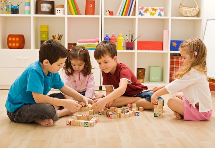 children play indoors with building blocks