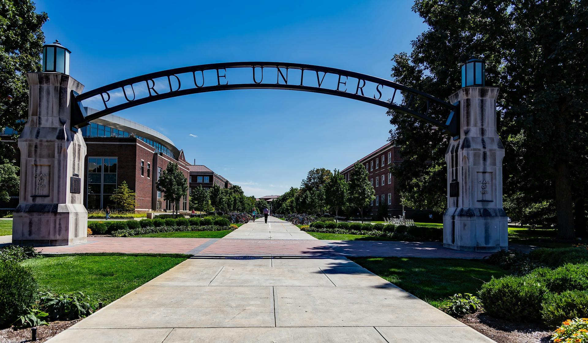The large Purdue University entrance archway spanning a paved walkway on a sunny day.