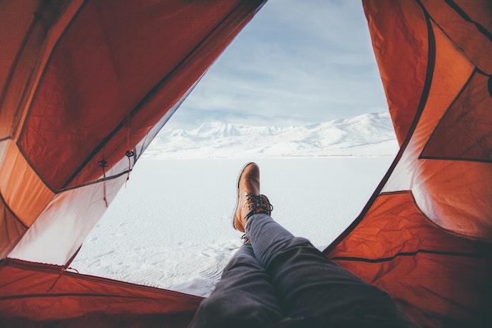 a man looks out of his tent into the view past his feet