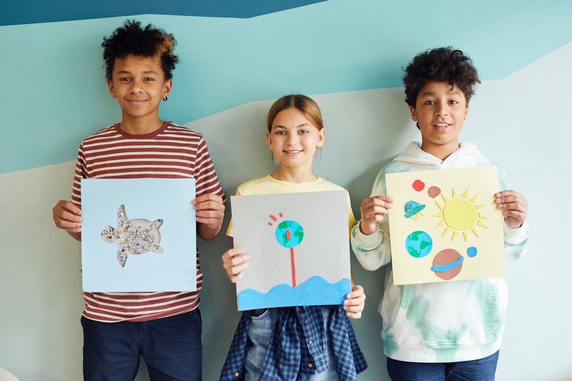 Young students holding their art projects