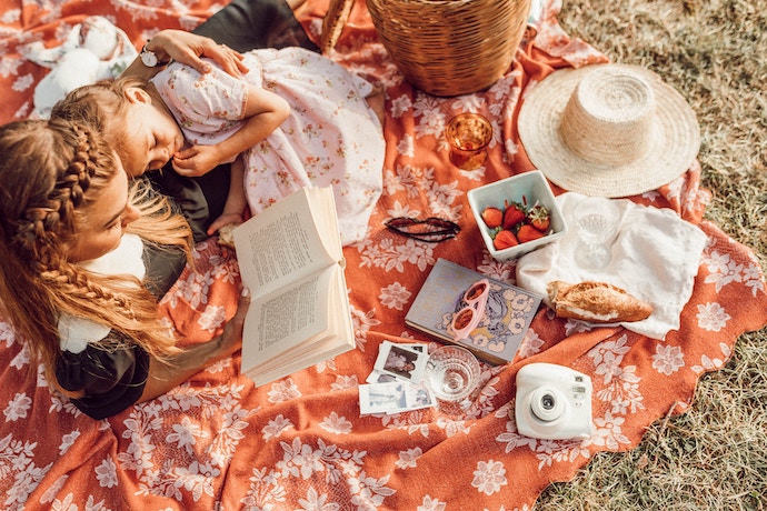 a mum and daughter enjoy reading together at a lovely picnic