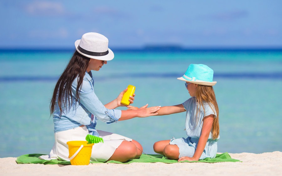 mum puts sun tan lotion on daughter