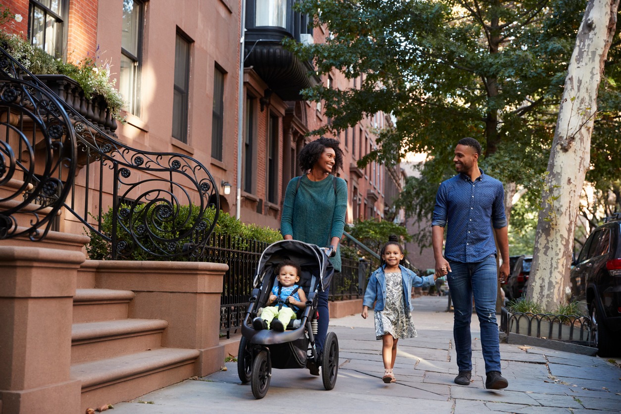 Young family walking on street pushing pram