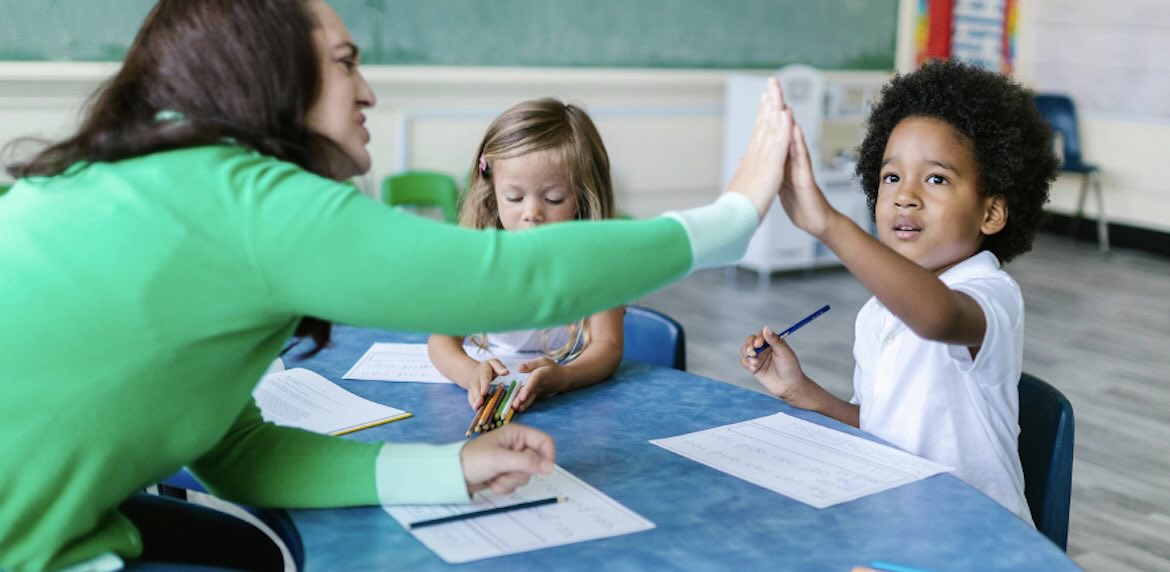 Teacher high fives child in class