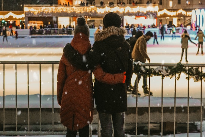 a couple watch ice skaters in a rink