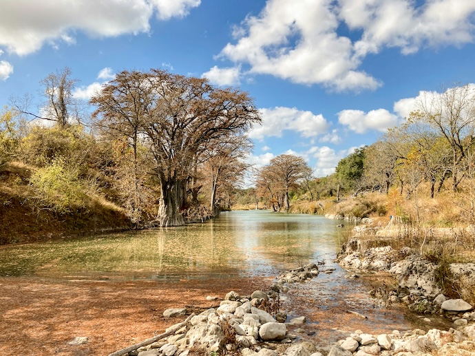 Autumn trees and foliage along the clear water of the Guadalupe River in Texas.
