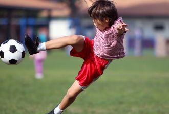 A young boy kicks a football in the garden