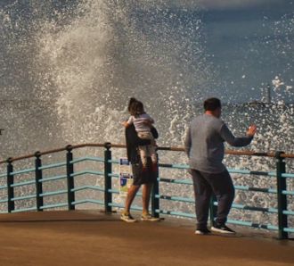Family watch as waves crash