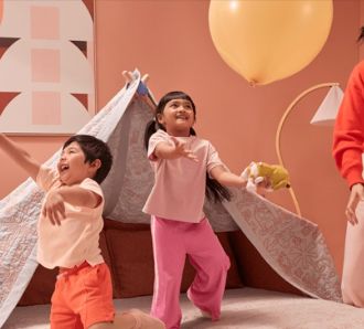 Kids playing balloons in blanket fort with parent