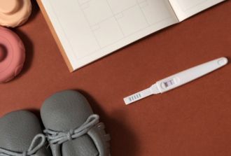 Pregnancy tester and baby items on a table
