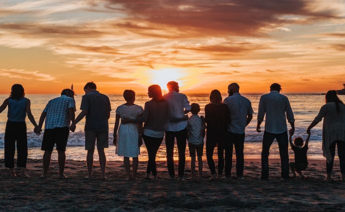 a number of families look out at the sea at sunset