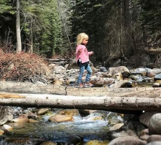 Dad and daughter on log over river