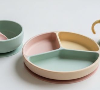 premium silicone baby tableware set in soft pastel colors, arranged aesthetically on a clean white table.
