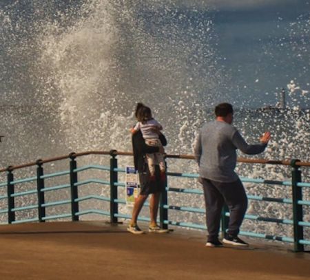 Family watch as waves crash