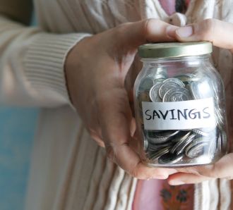 a hand holds a jar of coins saying savings