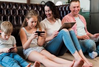 Family sitting on the floor holding different gadgets
