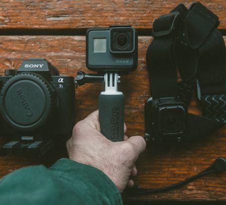 a hand holding a go-pro camera and equipment
