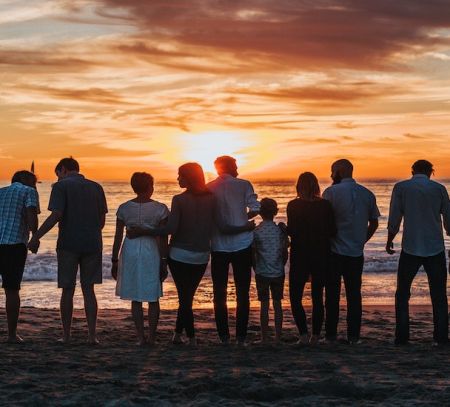 a number of families look out at the sea at sunset