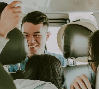 A happy group of young people laughing and talking together while riding inside a vehicle