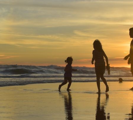 A family step into the sea at sunset