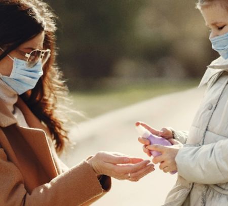 Mum giving daughter hand sanitsier