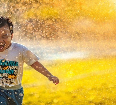 happy child runs through sprinkler