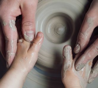a mum and kids hands on the potters wheel
