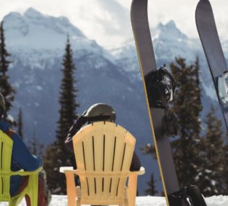 couple-sitting-chair-by-snowboards-snow-covered-mountain