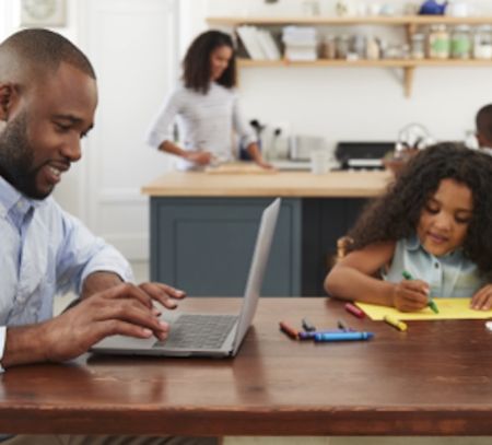 dad on laptop and daughter playing