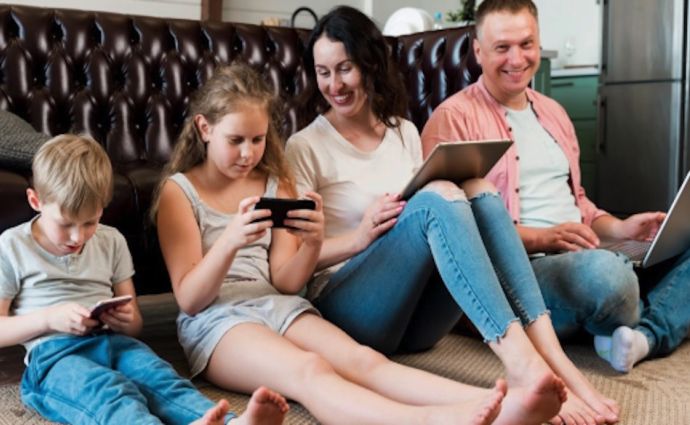 Family sitting on the floor holding different gadgets
