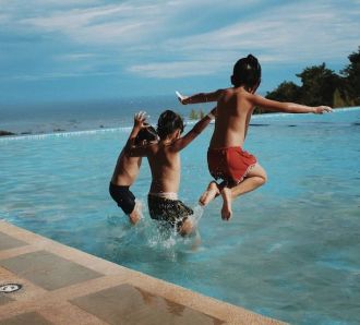 three boys jump in pool