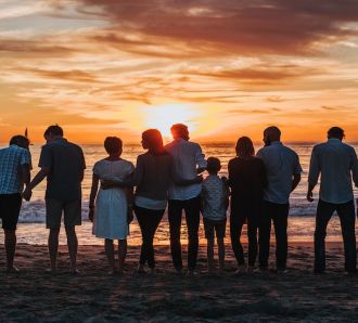 a number of families look out at the sea at sunset
