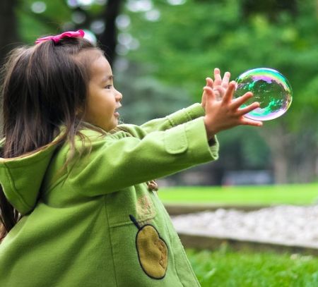 a young girl catches a bubble