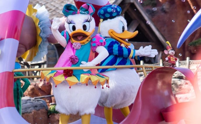 Donald and Daisy duck wave from a float