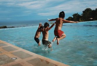 three boys jump in pool