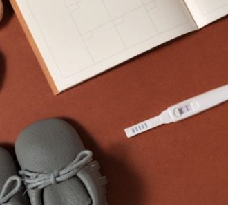 Pregnancy tester and baby items on a table