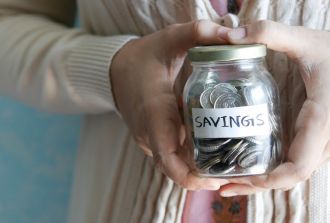 a hand holds a jar of coins saying savings