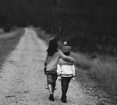 a brother and sister walk arm in arm