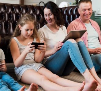 Family sitting on the floor holding different gadgets