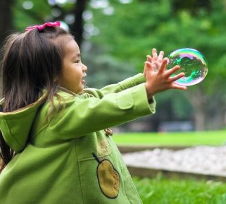 a young girl catches a bubble