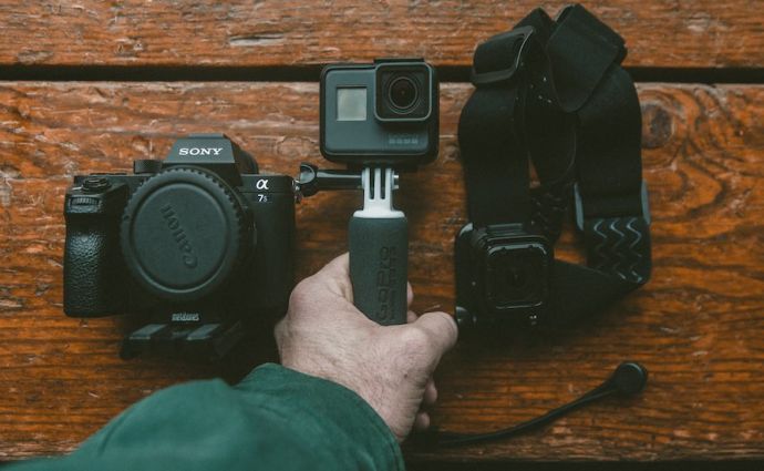 a hand holding a go-pro camera and equipment