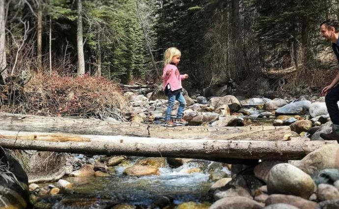 Dad and daughter on log over river