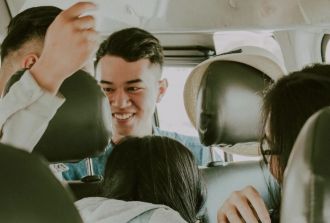 A happy group of young people laughing and talking together while riding inside a vehicle