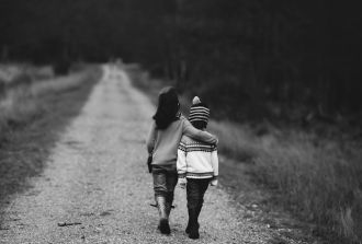 a brother and sister walk arm in arm