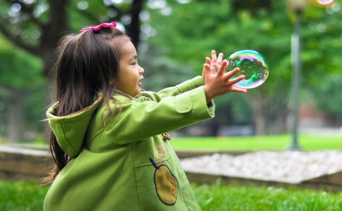 a young girl catches a bubble
