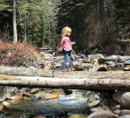 Dad and daughter on log over river