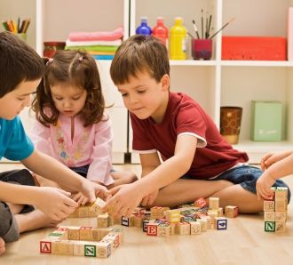 children play indoors with building blocks