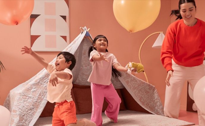 Kids playing balloons in blanket fort with parent